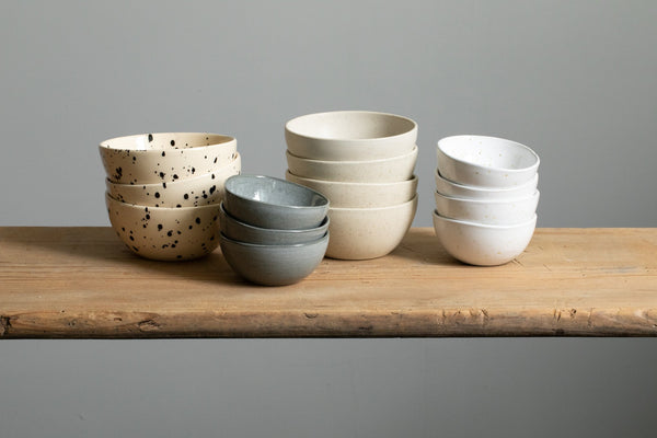 Four stacks of small bowls in different colors (white, grey, beige, light with black dots)