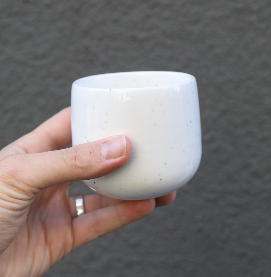 Latte Serra Keramik Cup für Latte Macchiate in Hand gehalten vor grauem Hintergrund.
