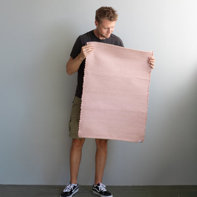 60x90cm petit tapis tenu par une personne en vieux rose rayé avec du jute tissé à la main au Portugal