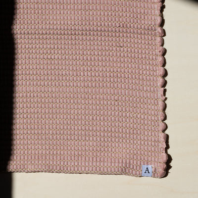 Close-up d'un petit tapis 60x90cm en vieux rose avec du jute entrelacé tissé à la main à partir de coton upcycling au Portugal