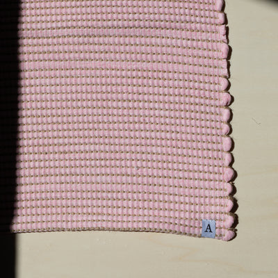 Close-up d'un petit tapis 60x90cm en rose avec du jute entrelacé tissé à la main en coton upcycling au Portugal