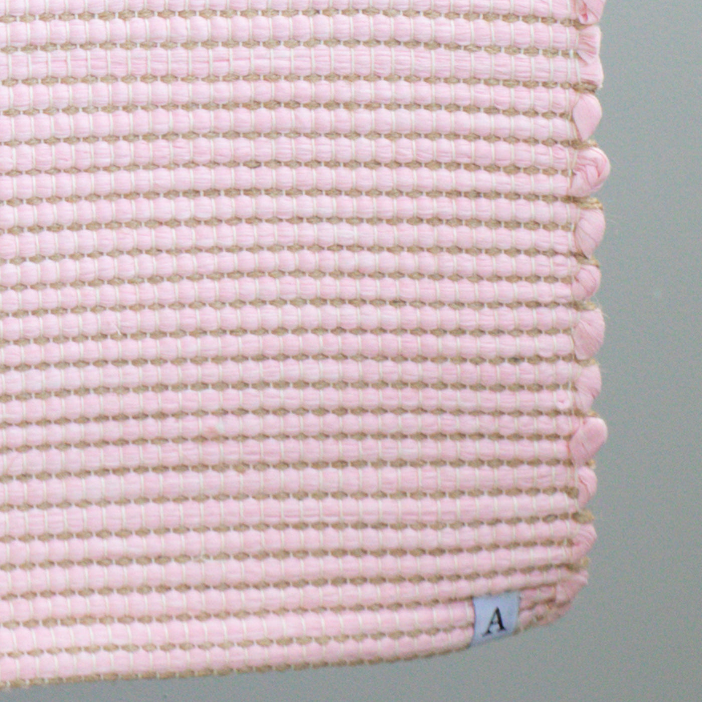 Close-up d'un tapis de bain rose à rayures de jute fabriqué à partir de chutes de laine de l'industrie textile et tissé à la main au Portugal