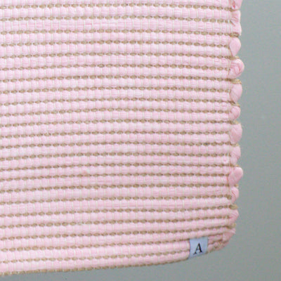 Close-up d'un tapis de bain rose à rayures de jute fabriqué à partir de chutes de laine de l'industrie textile et tissé à la main au Portugal