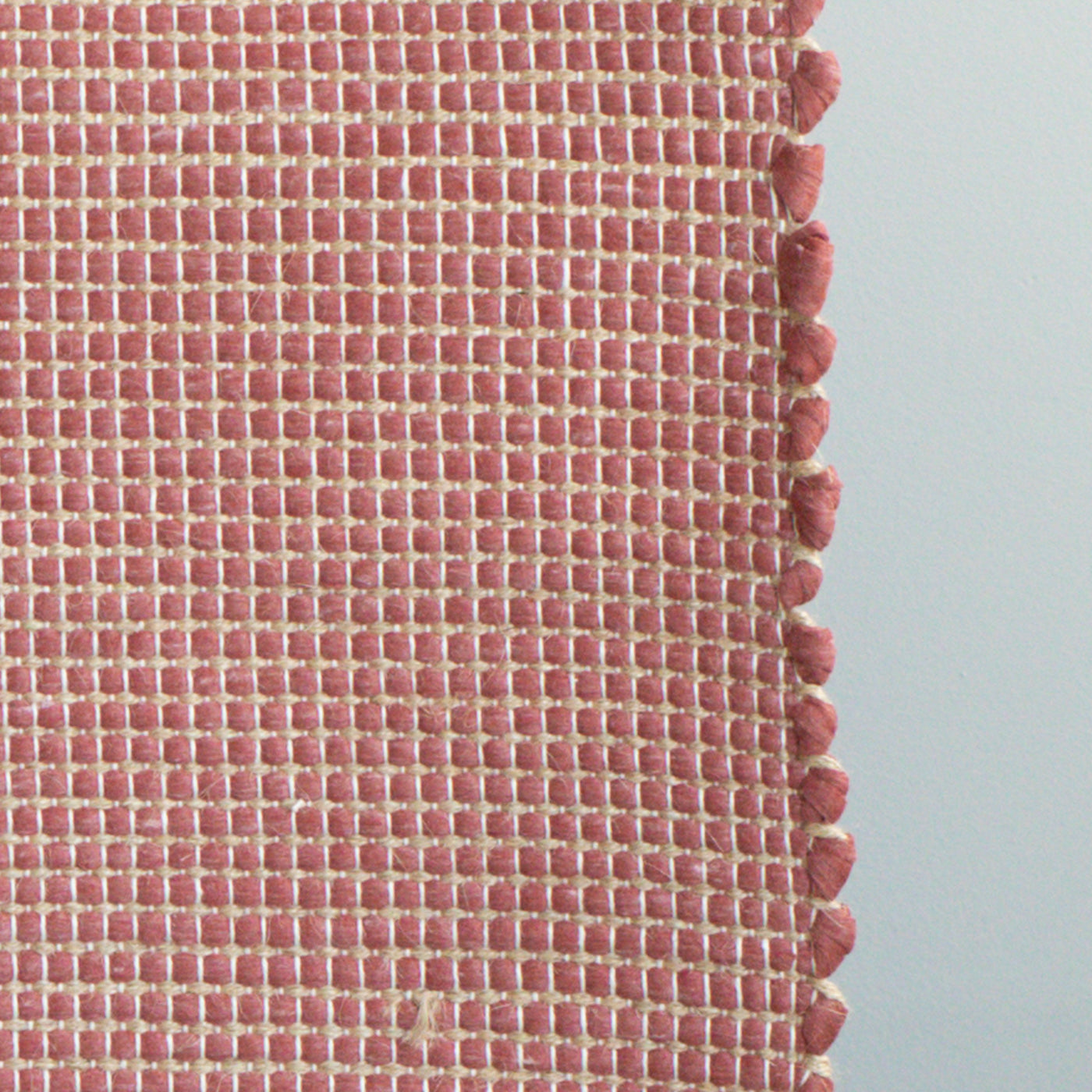 Close-up d'un tapis de bain rouge à rayures de jute fabriqué à partir de chutes de laine provenant de l'industrie textile et tissé à la main au Portugal