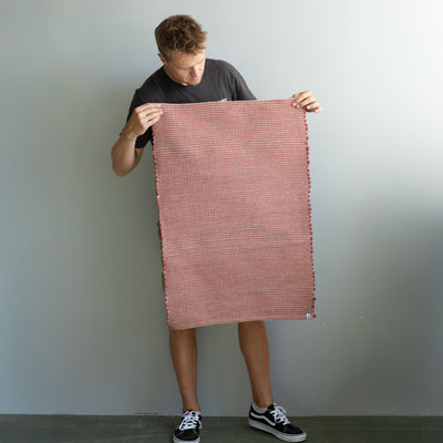 60x90cm petit tapis tenu par une personne en rouge rayé avec du jute tissé à la main au Portugal