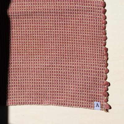 Close-up d'un petit tapis 60x90cm en rouge avec du jute entrelacé tissé à la main à partir de coton upcycling au Portugal
