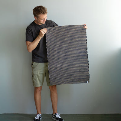 60x90cm petit tapis tenu par une personne en noir rayé avec du jute tissé à la main au Portugal