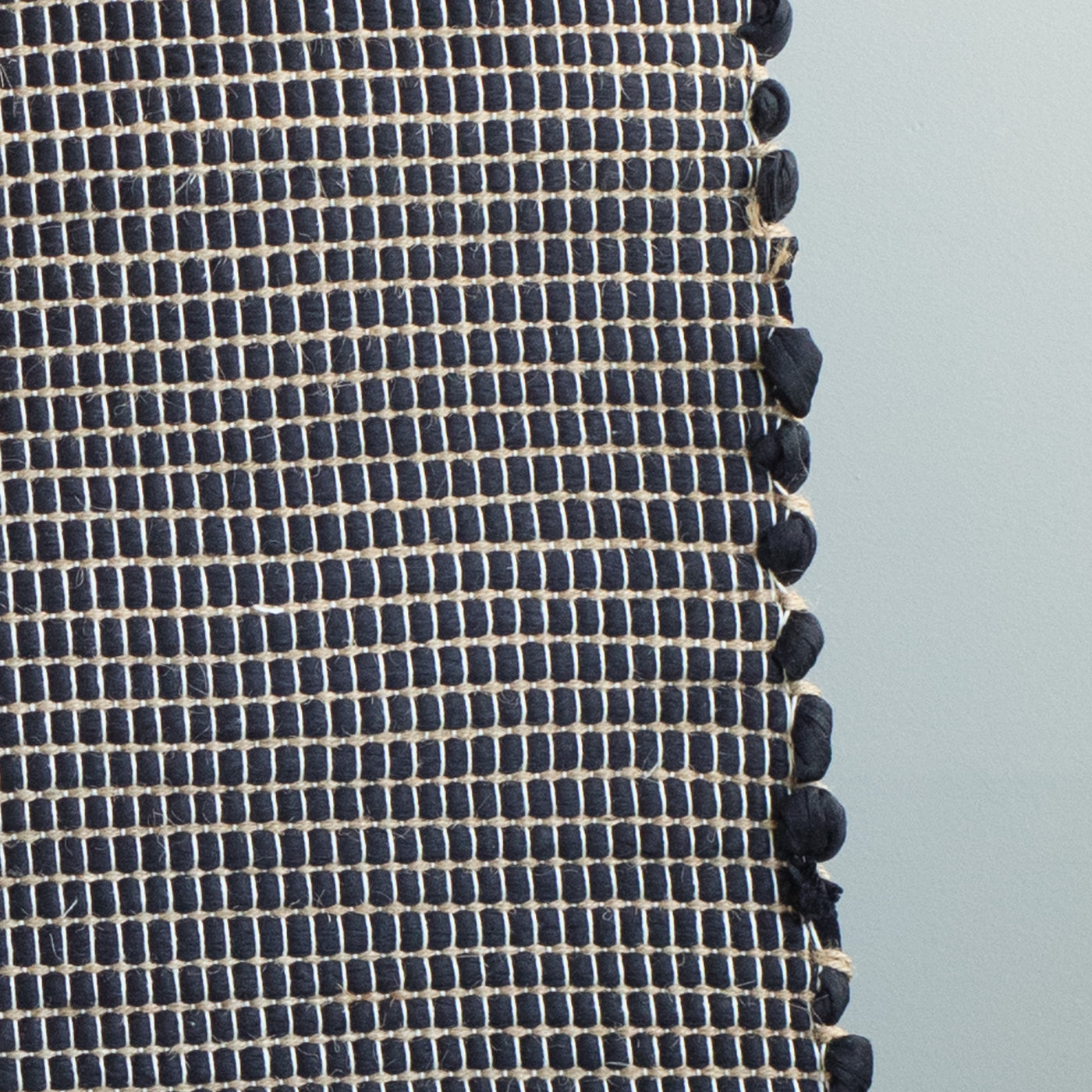 Close-up d'un tapis de salle de bain noir rayé de jute fabriqué à partir de chutes de laine provenant de l'industrie textile et tissé à la main au Portugal