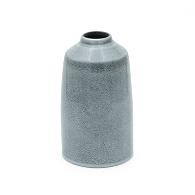 Vase bleu simple qui rétrécit vers le haut et offre une ouverture stable pour les bouquets de fleurs.