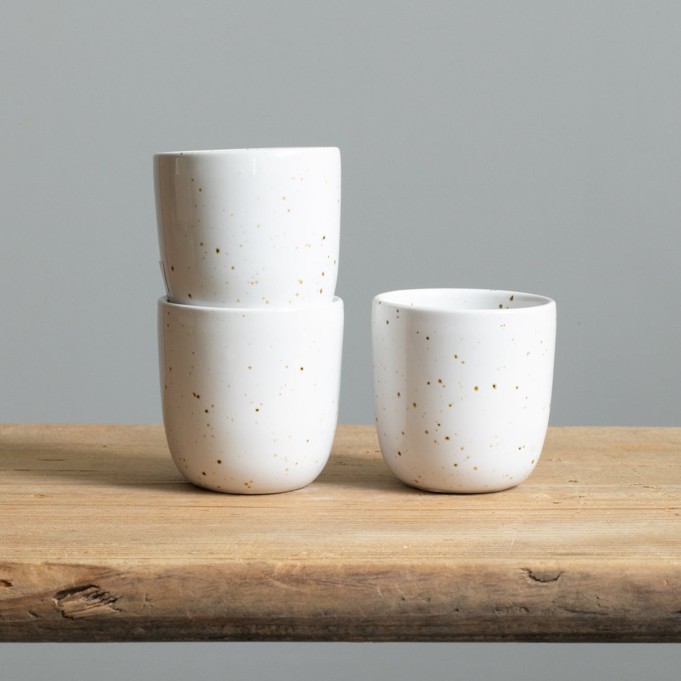Trois tasses à espresso blanches empilées avec de fines éclaboussures dorées