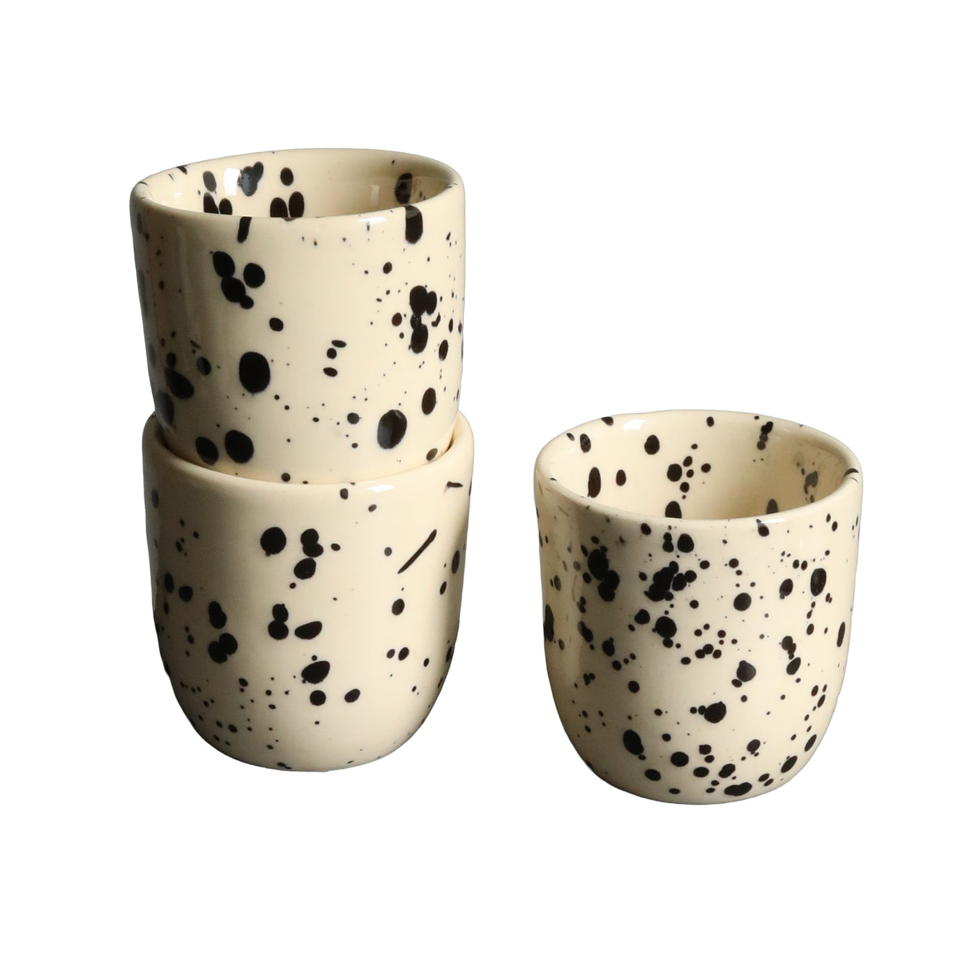 Zwei gestapelte und eine daneben stehende beige Espresso Tasse mit schwarzen Punkten freigestellt vor weissem Hintegrund.