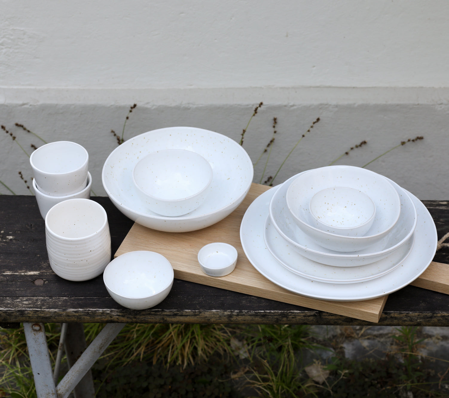 Mood image of white ceramic tableware photographed from above showing large and small plates, coffee cups, bowls and dishes in white