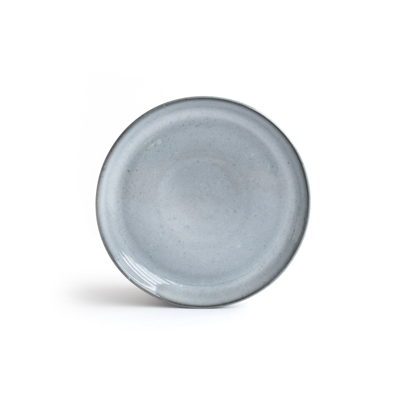 Petite soucoupe gris-bleu avec bord plus foncé détachée sur fond blanc