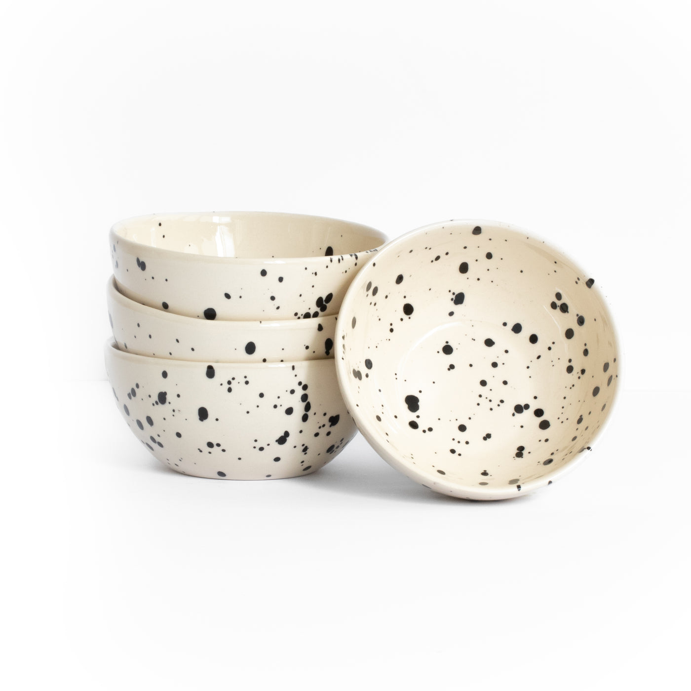 Trois grandes coupes empilées et une grande coupe posée pour les snacks, de couleur beige avec des points noirs sur fond blanc