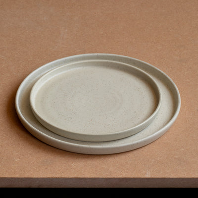 Kleiner Teller liegt in grossem Teller beide haben einen geraden Rand und sind matt beige