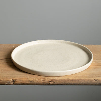 Matt beige large plate with straight rim lying on a wooden board