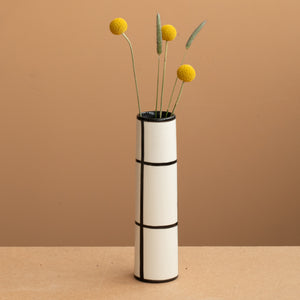 Dünne Vase in weisser Farbe schwarz kariert und gelben und grünen Blumen