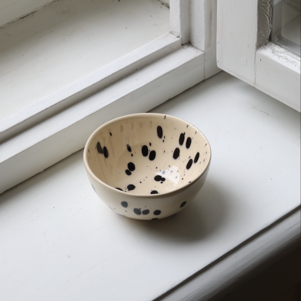 Small snack bowl with cream-colored glaze and black dots perfect for nuts and dips
