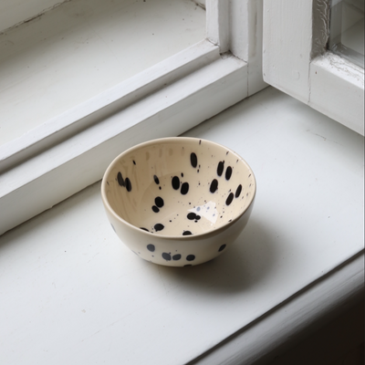 Small snack bowl with cream-colored glaze and black dots perfect for nuts and dips