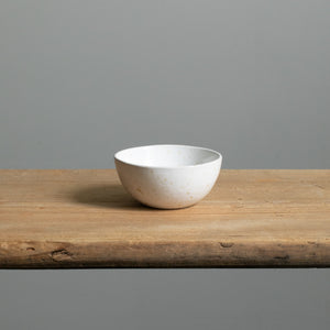 Front view of the small white snack bowl on a wooden board