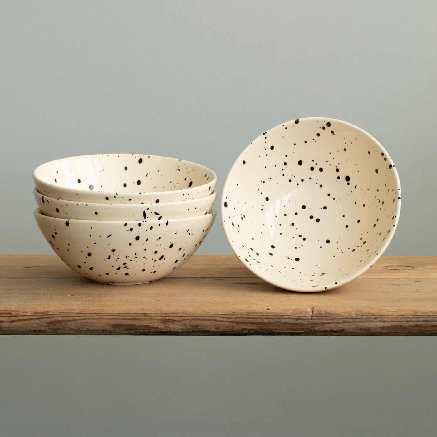 Drei aufeinander gestapelte Müesli Bowls in cremfarbe mit schwarzen Punkten und eine aufgestellte Schüssel