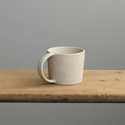 Tee Tasse mit Henkel in beige auf einem Holztisch