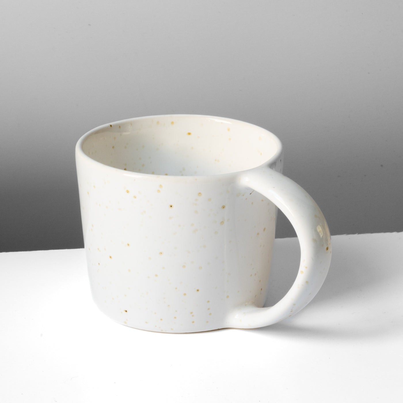Large white tea cup with fine golden speckles and large round handle