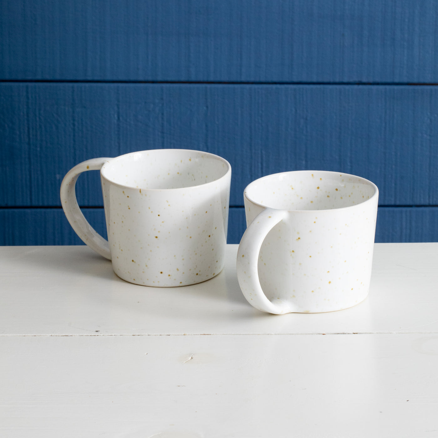 Two teacups with large handle in wide modern style with white reactive glaze made of stoneware