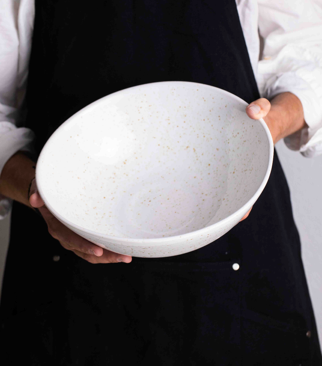 Large white salad bowl held by two hands.